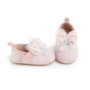Close-up of pink baby walking shoes with floral embroidery and large decorative bow