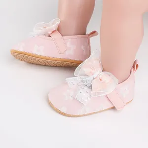 Close-up view of pink infant walking shoes featuring a white lace bow and floral pattern