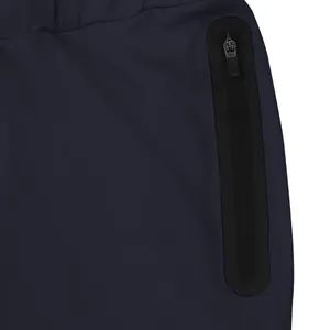 Detail view of the heat-sealed vertical zipper pocket on navy blue elastic athletic pants