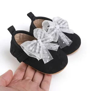 Detailed close-up of soft black baby walking shoes featuring elegant white mesh bow decorations
