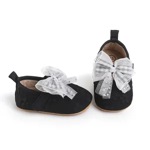 Close-up detail of black fabric infant walking shoes with elegant checkered mesh bow