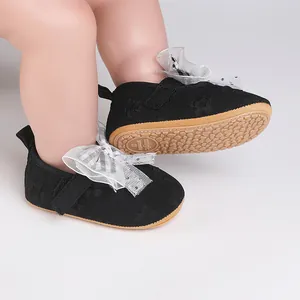 Detailed view of black baby walking shoes with white lace bow and anti-slip rubber sole