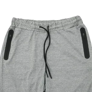 Close-up detail of men's grey sports joggers with elastic waistband and zipper pockets