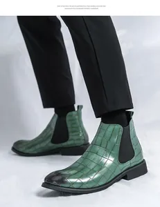 Botas Chelsea para hombre en cuero grabado verde mostradas con pantalones negros.