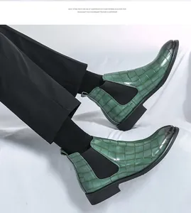 Detalle de botines Chelsea para hombre en piel verde con relieve de cocodrilo y pantalón