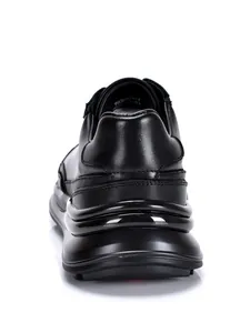 Detailansicht der Rückseite mit der klobigen Wellensohle eines schwarzen Sneakers