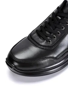 Nahaufnahme eines schwarzen Leder-Sneakers mit Schnürsenkeln und strukturiertem Mesh-Besatz