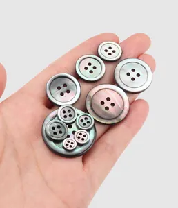 Close-up of premium Japanese iridescent shell buttons in various sizes held in hand