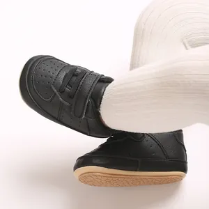 Dettaglio di scarpe da ginnastica per neonati in PU nero con suola in gomma morbida.