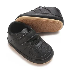 Dettaglio di scarpe neonato in PU nero con suola morbida e chiusura a strappo.