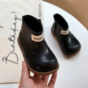 Close-up of black children's soft-sole leather boots with a side zipper closure.