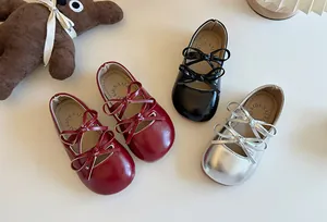 Vista dall'alto di ballerine per bambina con fiocco in rosso, nero e argento accanto a un orsetto.