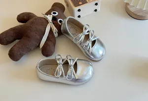 Primo piano di ballerine da bambina argento con doppio fiocco e finitura metallizzata