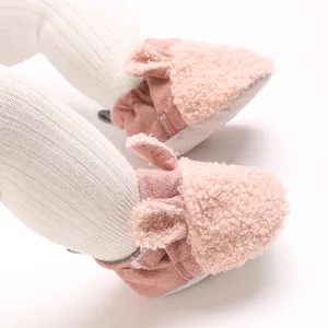 Nahaufnahme von rosa flauschigen Baby-Winterschuhen mit süßen Ohren und weicher Textur.