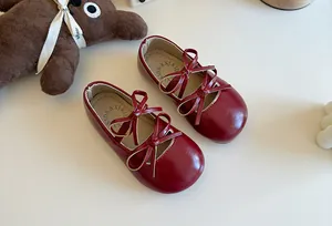 Primo piano di eleganti ballerine rosse per bambine con dettagli a doppio fiocco.