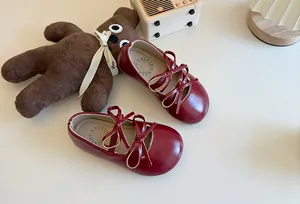 Dettaglio delle scarpe Mary Jane bordeaux da bambina con raffinati doppi fiocchi rossi.