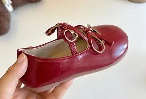 Primo piano di ballerine in vernice rossa per bambina con elegante doppio fiocco.