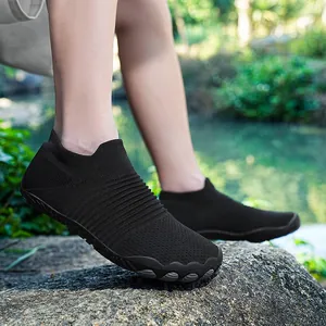 Gedetailleerd overzicht van zwarte barefoot schoenen met ademend gebreid bovenwerk op rotsen
