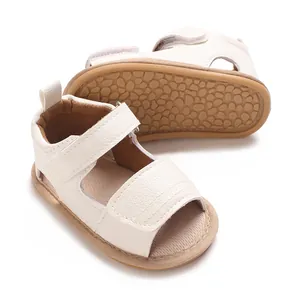 Gros plan de sandales pour bébés blanc cassé avec semelles en caoutchouc souples.