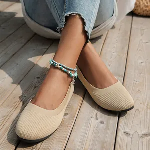 Close-up of women's beige breathable fly-knit ballet flats on a wooden deck