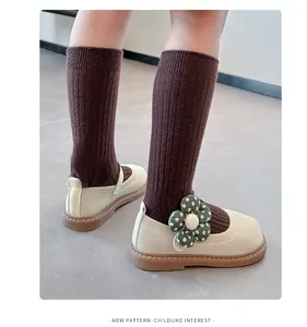 Detailaufnahme der gestrickten Prinzessinnenschuhe für Mädchen mit grüner Stoffblume