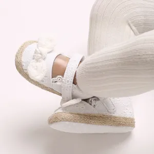 Detail van witte babyprinsessenschoenen met kantranden en een zachte strikknoop voor baby's.