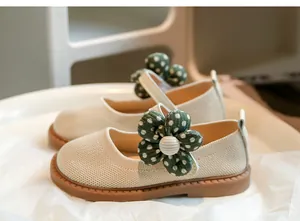 Detailaufnahme beiger Mädchen-Strickschuhe mit einer großen grünen gepunkteten Blume