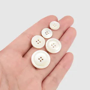 High-quality natural white shell buttons in five different sizes held in a palm