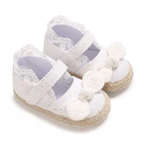 Gedetailleerde foto van witte kanten babyschoenen met een grote sierlijke strik.