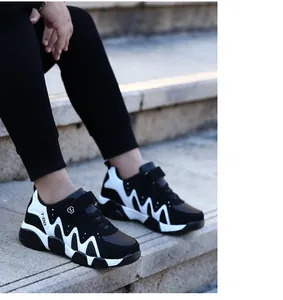 Detailed outdoor view of boys' black and white sneakers worn on stone steps for autumn