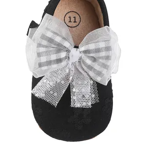 Detail view of baby girl princess shoe with white checkered bow and glitter lace