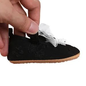 Close-up of black baby girl princess walking shoe with white lace bow and rubber sole