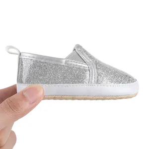 Macro detail of silver glitter baby walking shoe with soft non-slip sole for infants.