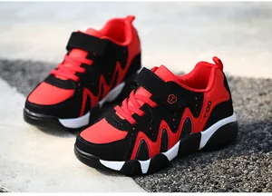 Detailed close-up of vibrant red and black boys' athletic running shoes outdoors