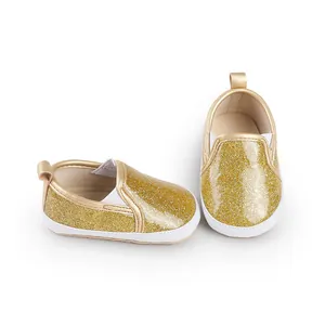 Close-up of golden glitter baby shoes with soft white soles and elastic sides