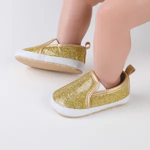 Close-up of sparkling gold glitter baby walker shoes worn by an infant on soft surface