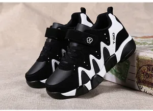 Side view detail of black and white kids' sports sneakers with hook-and-loop straps