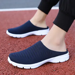 Detailed side view of breathable navy blue knit slip-on mules on a red outdoor athletic track