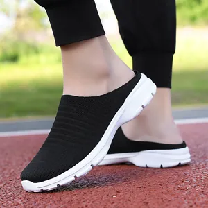 Macro detail of black fly-knit breathable slip-on mules with white sole on running track