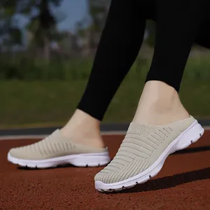 Detail view of beige breathable fly-knit slip-on mules on a red running track