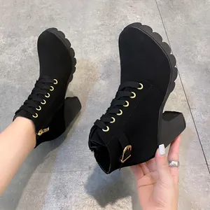 Detail schwarzer Stiefeletten mit Blockabsatz, Schnürung und goldener Schnalle.
