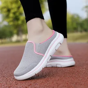 Side view of gray mesh breathable mule sneakers with pink trim on a track