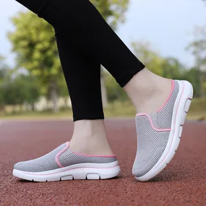 Side detail of women's breathable gray mesh mule sneakers with pink trim outdoors.