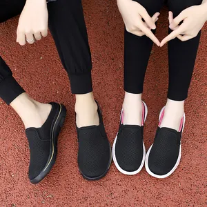 Top-down view of a couple wearing breathable black mesh slip-on sneakers on a track.