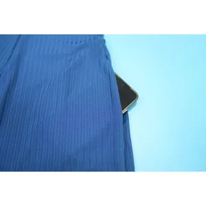Nahaufnahme der funktionalen Seitentasche an einem blauen, gerippten Jumpsuit-Stoff
