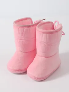 Close-up of soft pink plush baby snow boots with warm lining for infant winter walking