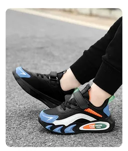 Detailansicht von schwarzen Jungen-Sneakern mit blauen Akzenten auf dem Asphalt