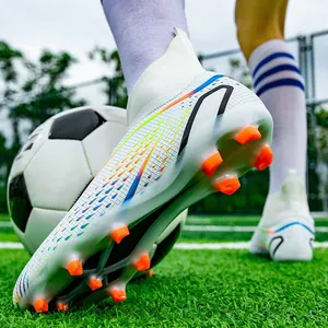 Detailansicht der weißen hohen Fußballschuhe mit orangefarbenen Stollen auf dem Rasen