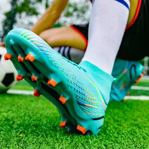 Nahaufnahme türkisfarbener hoher Fußballschuhe mit orangen Stollen auf Rasen