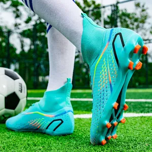 Professionelle türkisfarbene Fußballschuhe mit orangefarbenen Stollen auf grünem Rasen
